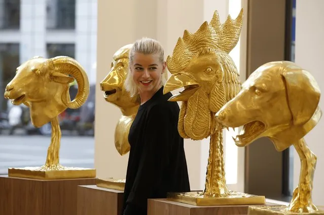 An auction house employee poses for the photographers in front of gold plated zodiac heads, part of the 2010 art piece by Chinese artist Ai Weiwei, entitled: “Circle of Animals/Zodiac Heads”, during a photo call in central London, Monday, February 9, 2015. According to Phillips auction house, the zodiac heads are inspired by those which once comprised a water clock-fountain at the Old Summer Palace, the celebrated masterpiece of Chinese landscape design. (Photo by Lefteris Pitarakis/AP Photo)