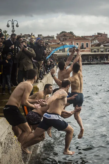 Pilgrims jump into the water to retrieve a cross during an Epiphany ceremony to bless the water in Mytilene port on the northeastern Greek island of Lesbos, Wednesday, January 6, 2016. Similar ceremonies to mark Epiphany Day were held across Greece at the sea, rivers, lakes and dams. An Orthodox priest throws a cross into the water and the swimmers race to retrieve it first. (Photo by Santi Palacios/AP Photo)
