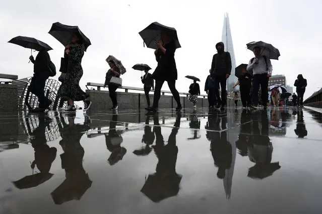 Commuters carry umbrellas while crossing London Bridge in London, Britain on August 2, 2023. (Photo by Hollie Adams/Reuters)