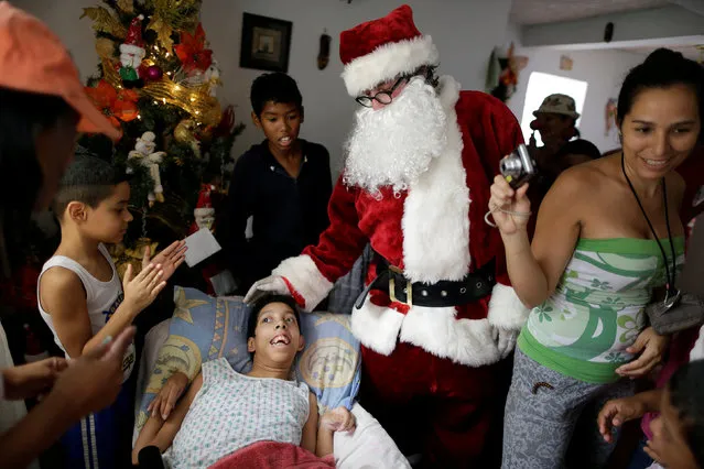Santa Claus greets a child during a visit to residents of the slum of Petare in Caracas, Venezuela, December 11, 2016. (Photo by Ueslei Marcelino/Reuters)