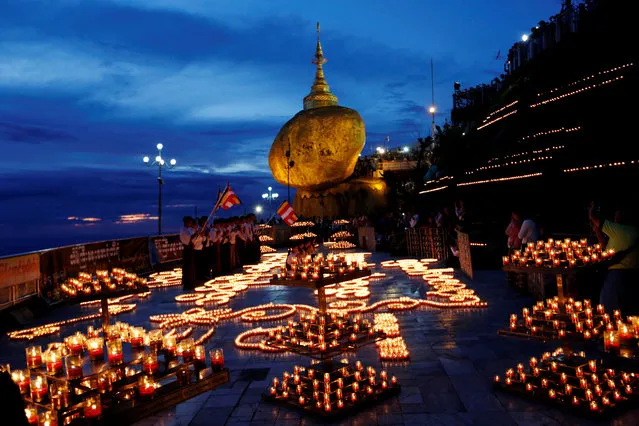 Buddhist pilgrims light candles around the Golden Rock or Kyaikhtiyo Pagoda to celebrate the full moon festival in Kyaikto, Mon state, Myanmar on October 24, 2018. (Photo by Ann Wang/Reuters)