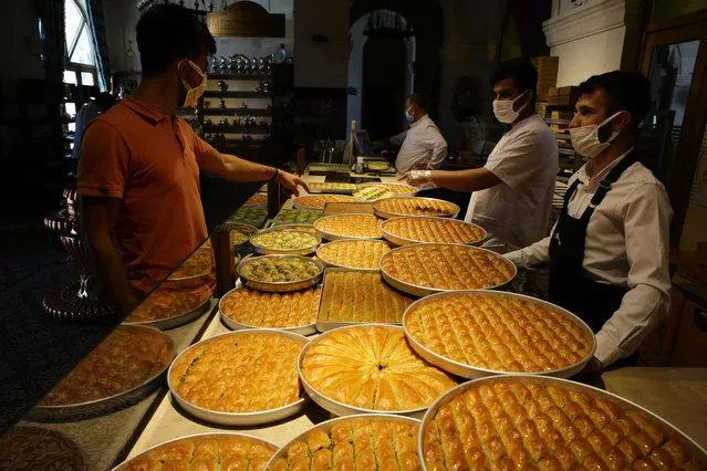 Trays of baklava species are seen in a baklava bakery ahead of the Eid Al-Fitr in Gaziantep, Turkey on May 10, 2021. Baklava is a rich, sweet pastry made of very thin layers of filo and is held together by sugar syrup or honey and filled with various types of nuts, most commonly pistachios. (Photo by Mehmet Akif Parlak/Anadolu Agency via Getty Images)