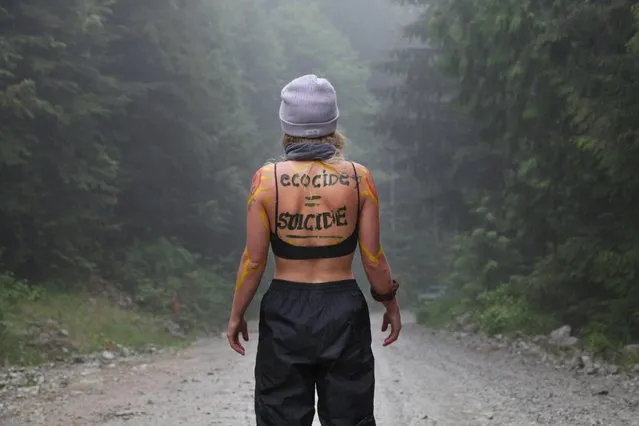 A woman stands near a blockade of protesters against old growth timber logging in the Fairy Creek area of Vancouver Island, near Port Renfrew, British Columbia, Canada on May 24, 2021. Environmentalists camped out in the dense coastal rainforest say they are fighting Canada's version of the ivory trade. The region features towering old-growth trees, such as cedars, Douglas firs and western hemlocks aged at least 250 years, and in some cases more than a thousand. (Photo by Jen Osborne/Reuters)