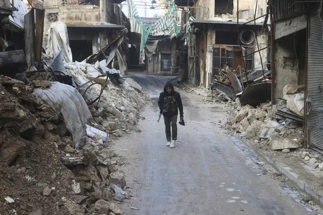 A Free Syrian Army fighter walks with his weapon amid damaged buildings in Old Aleppo January 17, 2015. (Photo by Abdalrhman Ismail/Reuters)