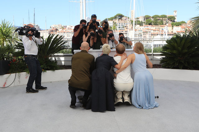(FromL) Russian actor Yuri Kolokolnikov, Russian actress Chulpan Khamatova, Russian actor Ivan Dorn and Russian actress Yuliya Peresild hide behind the podium during a photocall for the film “Petrov's Flu” at the 74th edition of the Cannes Film Festival in Cannes, southern France, on July 13, 2021. (Photo by Valery Hache/AFP Photo)