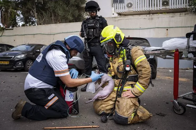 A firefighter and a paramedic deliver oxygen to an injured cat rescued from a building struck by a rocket fired from Gaza, in Tel Aviv, Israel, Friday, October 27, 2023. (Photo by Oded Balilty/AP Photo)
