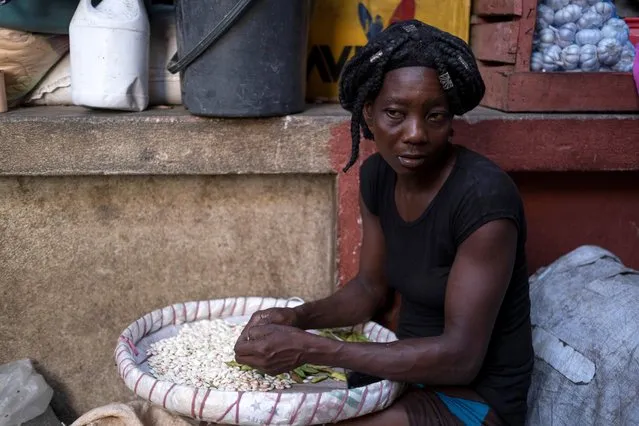 A woman peels beans at a fresh market in Port-au-Prince, Haiti on July 17, 2021. (Photo by Ricardo Arduengo/Reuters)