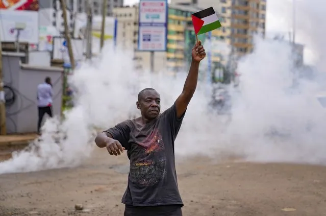 A demonstrator waves a Palestinian flag as Kenyan police officers fire teargas canisters during a protest against Israel and in support of Palestinians, in Nairobi, Kenya, Thursday, November 9, 2023. (Photo by Brian Inganga/AP Photo)