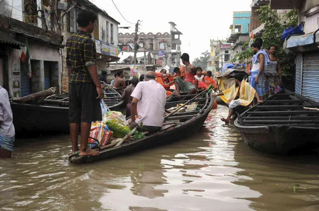 Villagers prepare to move to higher grounds on boats after heavy rain inundated their houses at Khanakul, Hooghly district, West Bengal state, Wednesday, August 4, 2021. (Photo by Ashim Paul/AP Photo)