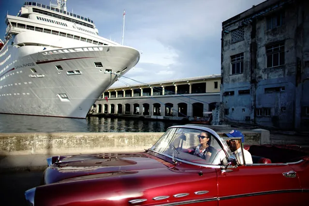 People ride in a vintage car next to a cruise ship docked in Havana, Cuba on August 23, 2018. (Photo by Alexandre Meneghini/Reuters)