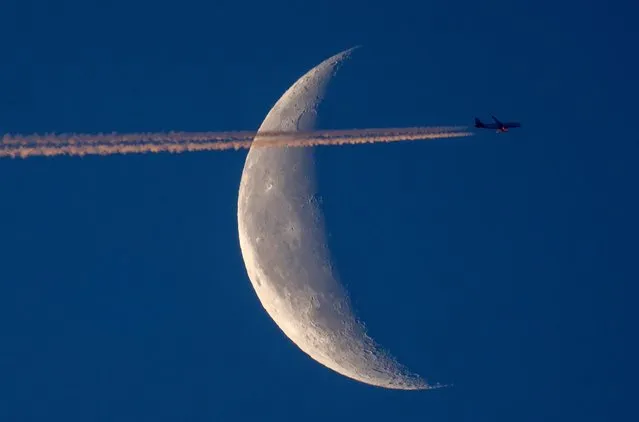 An aircraft passes by the moon in Frankfurt, Germany, Tuesday, June 13, 2023. (Photo by Michael Probst/AP Photo)