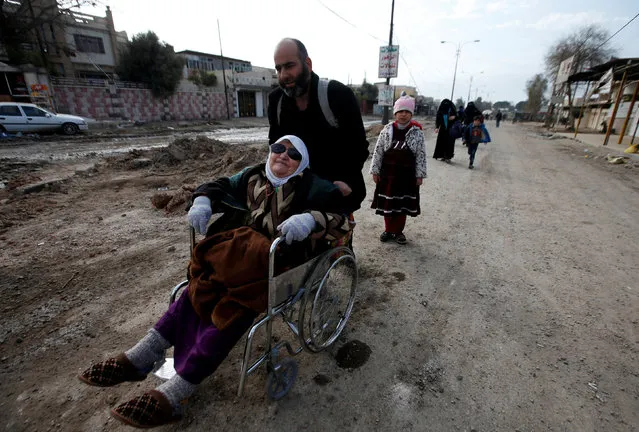 A displaced Iraqi man pushes a woman in a wheelchair as they flee during a battle with Islamic State militants, in al-Zuhoor neighborhood of Mosul, Iraq, January 8, 2017. (Photo by Azad Lashkari/Reuters)