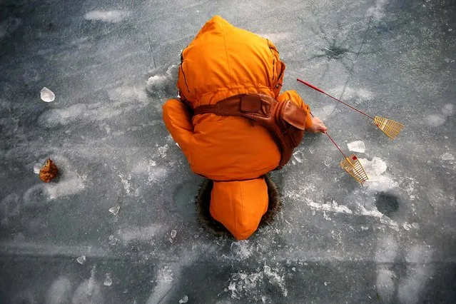 A woman fishes for trout through a hole in a frozen river in Hwacheon, South Korea, on January 4, 2014. (Photo by Kim Hong-Ji/Reuters)