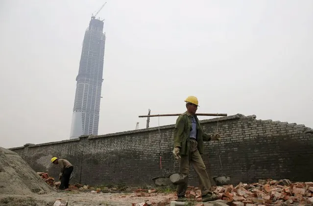 Labourers work at the construction site of an official building next to the unfinished 438-metre-high Wuhan Centre in Wuhan, Hubei province, April 18, 2015. (Photo by Reuters/Stringer)