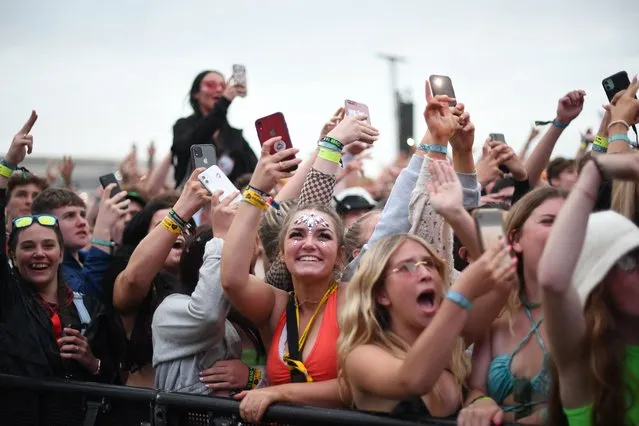Festival-goers hold up their mobile phones as they watch British rapper AJ Tracey perform on stage at Reading Festival in Reading, west of London, on August 27, 2021. As coronavirus covid-19 infection levels rise across the country, vaccines will be offered to revellers throughout the weekend. The organiser of Reading and Leeds Festivals has said such events are arguably “safer places to be” because attendees have been tested for covid-19. The festivals are returning this year with headliners including Stormzy, after being cancelled last year due to the pandemic. (Photo by Daniel Leal-Olivas/AFP Photo)