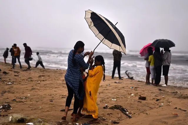 A woman tries to hold an umbrella amidst gusty winds as Cyclone Michaug is expected to make landfall on the eastern Indian coast, at Foreshore Estate Beach, in Chennai, India, 03 December 2023. The Indian Meteorological Department has issued a red alert for heavy rains in Chennai as the cyclonic storm, “Cyclone Michaung” is anticipated to make landfall between Andhra Pradesh's Nellore and Machilipatnam on December 05. (Photo by Idrees Mohammed/EPA/EFE)