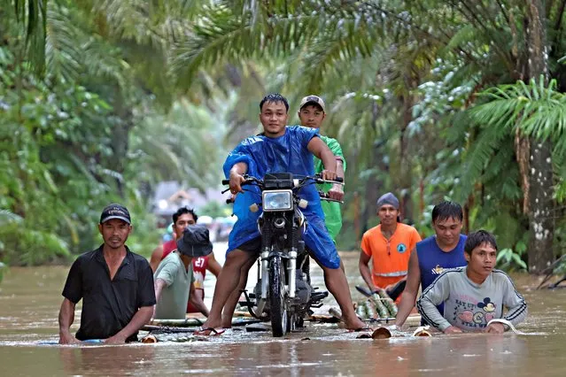 Residents push a makeshift raft loaded with a motorcycle through floodwaters brought about by heavy rains in Propseridad town, Agusan del Sur province on southern Mindanao island on February 1, 2024. Floods and landslides triggered by torrential rain have killed six people in the Philippines, with one other person missing, rescuers said February 1. (Photo by Erwin Mascarinas/AFP Photo)