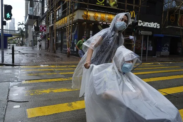People make their way on an empty street as Typhoon Kompasu passes in Hong Kong Wednesday, October 13, 2021. Hong Kong suspended classes, stock market trading and government services as the typhoon passed south of the city Wednesday. (Photo by Vincent Yu/AP Photo)