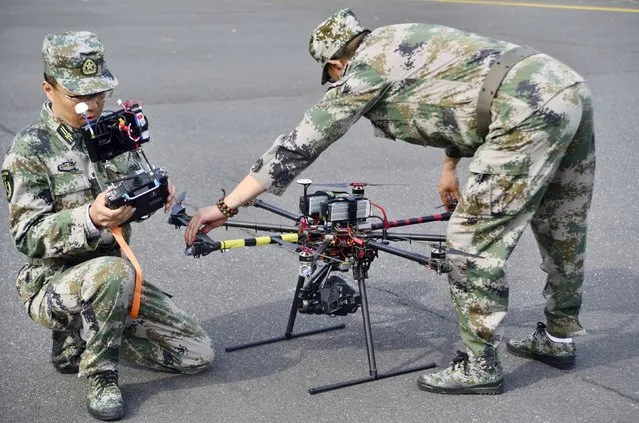 A pair of militia members prepare to fly drones during a test in Shanghai, China, April 21, 2015. China is stepping up research into military drones as its arms industry looks to increase export volumes, hoping to gain traction with cheaper technology and a willingness to sell to countries Western states are reluctant to. (Photo by Reuters/Stringer)