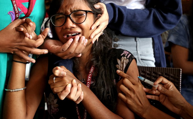 A woman reacts as she receives a shot of a vaccine against COVID-19 during a vaccination drive for college students, in Bangalore, India, 13 October 2021. India registered 15,283 new coronavirus and 226 deaths in the last 24 hours. (Photo by Jagadeesh N.V./EPA/EFE)