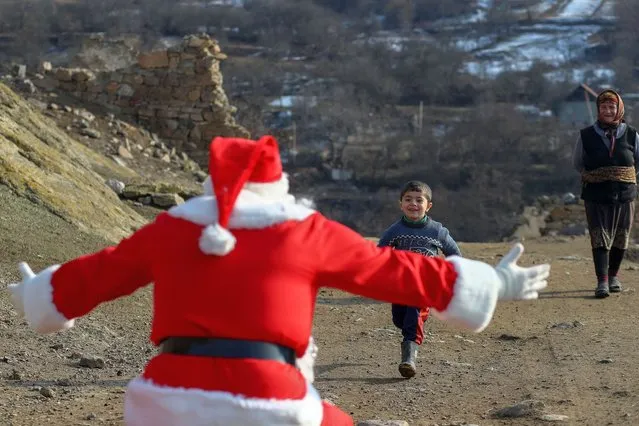 A man dressed as Santa Claus walks through the village to deliver gifts on December 25, 2022 in Dashkasan, Azerbaijan. Although Christmas is not a national holiday in Azerbaijan, many see it as an opportunity to be charitable. (Photo by Aziz Karimov/Getty Images)