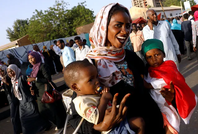 A protester holding her babies makes the victory sign during a demonstration in front of the Defence Ministry in Khartoum, Sudan April 22, 2019. (Photo by Umit Bektas/Reuters)