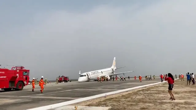 An evacuated passenger records on her phone as firefighters attend to the scene after Myanmar National Airlines flight UB103 landed without a front wheel at Mandalay International Airport in Tada-U, Myanmar May 12, 2019 in this still image taken from social media video. (Photo by Nay Min via Reuters)
