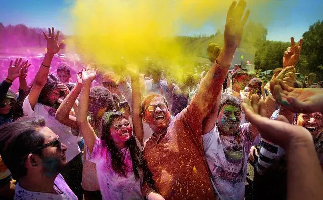 A crowd of celebrants toss colored powder into the air during the Festival of Colors at the India Cultural Center and Temple Saturday, April 2, 2016 in Memphis, Tenn. Throwing color is a traditional Hindu way to enthusiastically embrace the changing season and hundreds of Memphians turned out to usher in the spring with a color run, dancing, and traditional Indian food. (Photo by Jim Weber/The Commercial Appeal/AP Photo)