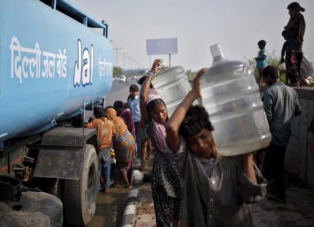 Slum dwellers carry drinking water containers which they filled from a water tanker provided by the state-run Delhi Jal (water) Board on a hot summer day in New Delhi, India, May 11, 2015. Temperature in Delhi on Monday reached 42.3 degree Celsius (108.14 degree Fahrenheit), according to India's metrological department website. (Photo by Anindito Mukherjee/Reuters)