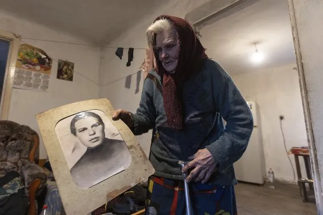 Halyna Moroka holds a portrait of her younger self in her house in the village of Nevelske in eastern Ukraine, Friday, December 10, 2021. The 7-year-old conflict between Russia-backed separatists and Ukrainian forces has all but emptied the village. “We have grown accustomed to the shelling”, said Moroka, 84, who has stayed in Nevelske with her disabled son. (Photo by Andriy Dubchak/AP Photo)