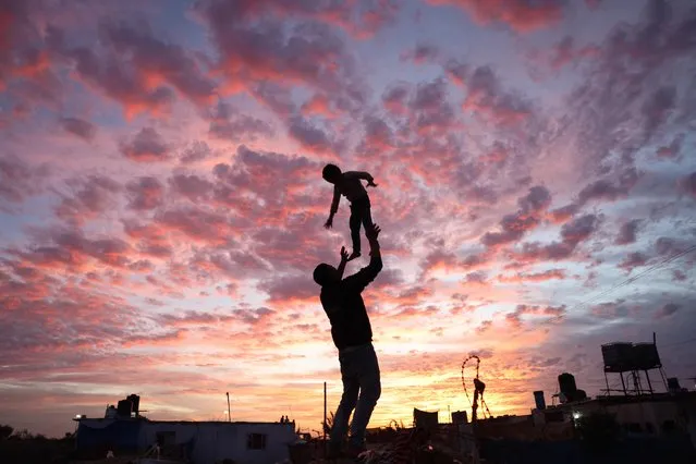 A Palestinian man plays with a child during sunset in Rafah in the southern Gaza Strip on December 4, 2021. (Photo by Mohammed Abed/AFP Photo) 