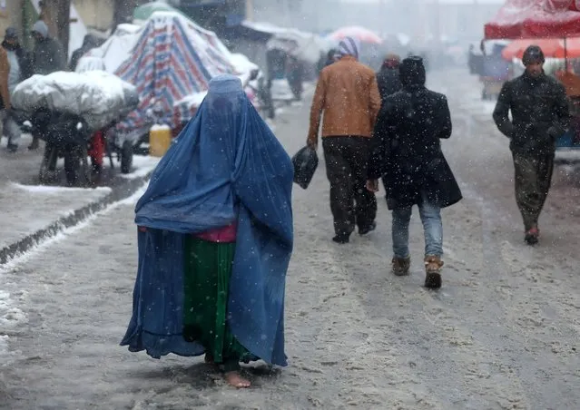An Afghan woman walks on the street during a snowfall in Kabul, Afghanistan, January 3, 2022. (Photo by Ali Khara/Reuters)