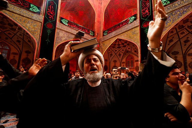 A Shi'ite cleric places a copy of the Koran on his head during commemorations of the death of Imam Ali during the holy month of Ramadan at the shrine of Imam Ali in the holy city of Najaf, Iraq, on April 1, 2024. (Photo by Alaa Al-Marjani/Reuters)