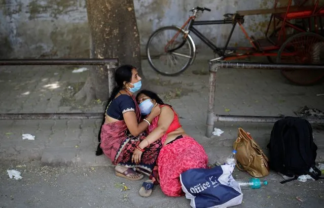 Women mourn the death of a family member, who died from the coronavirus disease (COVID-19), outside a crematorium in New Delhi, India April 24, 2021. (Photo by Adnan Abidi/Reuters)