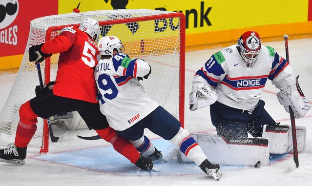 Switzerland's forward #59 Dario Simion (L) vies for a puck with Norway's defender #49 Christian Kasastul (C) and Norway's goalkeeper #31 Jonas Arntzen (R) during the IIHF Ice Hockey Men's World Championships match between Switzerland and Norway in Prague, Czech Republic on May 10, 2024. (Photo by Michal Cizek/AFP Photo)