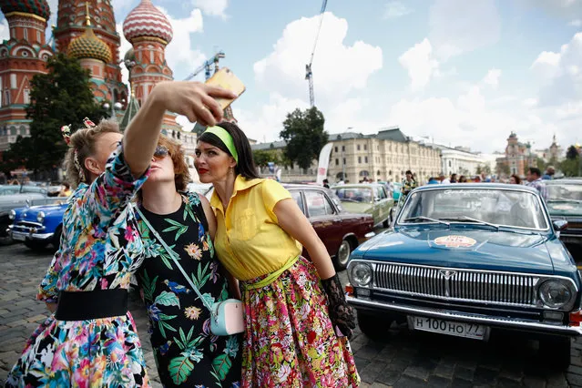 Woman take a selfie by a vintage car during the 2019 GUM Motor Rally featuring classic cars in Moscow, Russia on July 28, 2019. (Photo by Artyom Geodakyan/TASS via Getty Images)