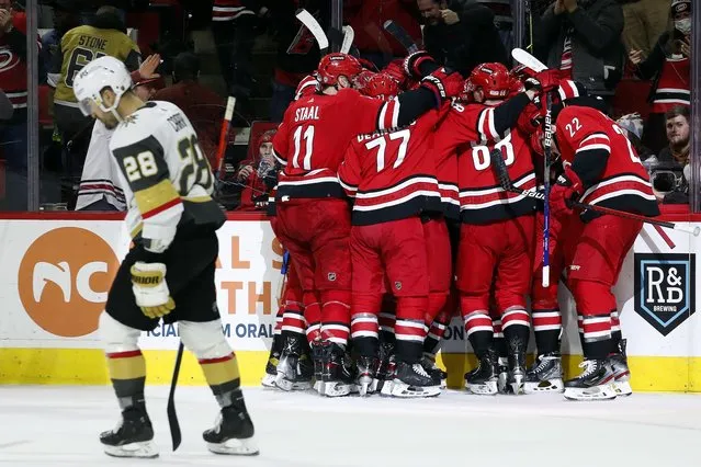 The Carolina Hurricanes celebrate an overtime goal by Sebastian Aho as Vegas Golden Knights' William Carrier (28) skates by during an NHL hockey game in Raleigh, N.C., Tuesday, January 25, 2022. (Photo by Karl B. DeBlaker/AP Photo)