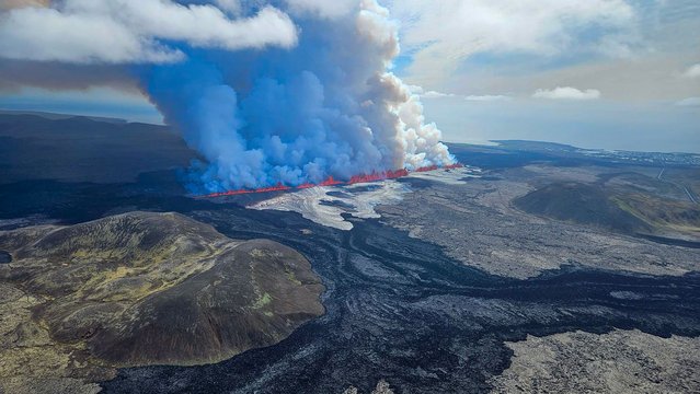 This handout picture released by the Icelandic Coast Guard on May 29, 2024 shows billowing smoke and flowing lava pouring out of a new fissure, during a surveilance flight above a new volcanic eruption on the outskirts of the evacuated town of Grindavik, western Iceland. A new volcanic eruption has begun on the Reykjanes peninsula in southwestern Iceland, the country's meteorological office said Wednesday, shortly after authorities evacuated the nearby town of Grindavik. (Photo by Icelandic Coast Guard/Handout via AFP Photo)