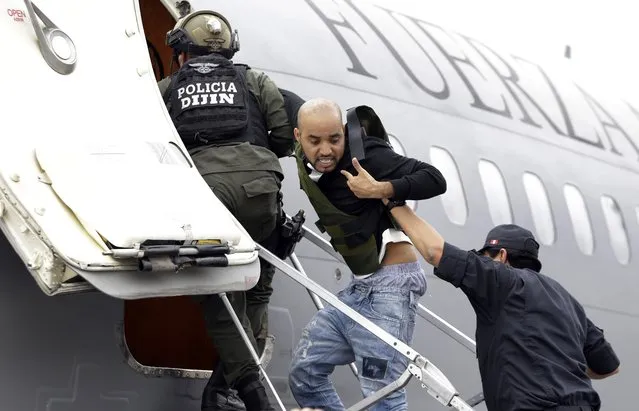 Alleged Peruvian drug trafficker Gerson Galvez, left, shouts at the press as he is escorted by a police officers into a Peruvian Air Force plane, in Bogota, Colombia, Sunday, May 1, 2016. Galvez who is one of Peru's most wanted criminals was captured by the Colombian police in Medellin on Saturday and was handed over to the Peruvian authorities. (Photo by Fernando Vergara/AP Photo)