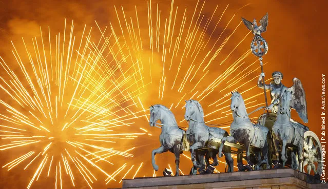 Fireworks explode over the Quadriga statue atop the Brandenburg Gate on New Year's Eve on January 1, 2012 in Berlin