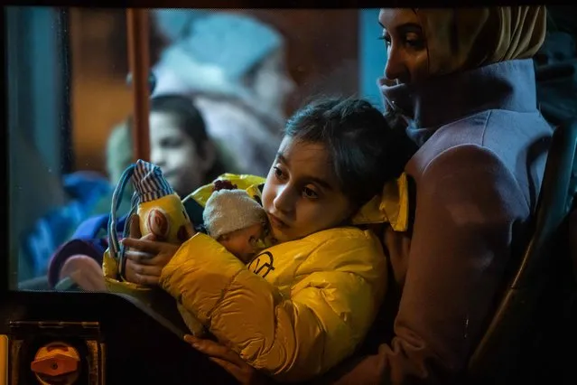A young refugee coming from Ukraine sit on a woman's lap inside a bus after arriving at the North Railway Station in Bucharest, early March 4, 2022. Refugees from Ukraine flock into Romania to escape Russia's invasion and avoid massive jams at the Polish border. The tide of stunned refugees continues, with Ukrainians appearing in their thousands at train stations in neighbouring European countries to be welcomed by volunteers handing them water, food and giving them medical treatment Both the EU and the United States said they would approve temporary protection for all refugees fleeing the war – numbered by the United Nations at more than one million and counting. (Photo by Mihai Barbu/AFP Photo)