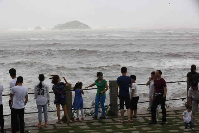Spectators watch strong waves ahead of the landfall of Typhoon Chan-Hom along the seashore in Wenling in eastern China's Zhejiang province Friday July 10, 2015. (Photo by Chinatopix via AP Photo)