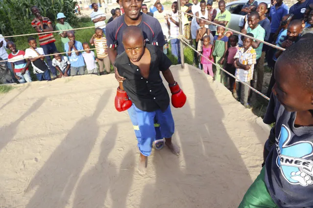 In this February 12, 2017 photo, a young boy is restrained by a referee during a boxing match in Chitungwiza about 30 kilometres south east of Harare. (Photo by Tsvangirayi Mukwazhi/AP Photo)
