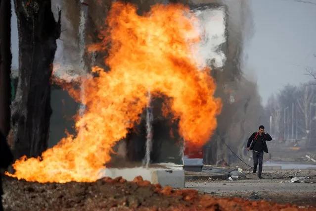 A man walks past a burning gas pipeline that was hit during shelling from Russian positions in a neighbourhood in northern Kharkiv as Russia's attack on Ukraine continues, Ukraine, March 31 2022. (Photo by Thomas Peter/Reuters)