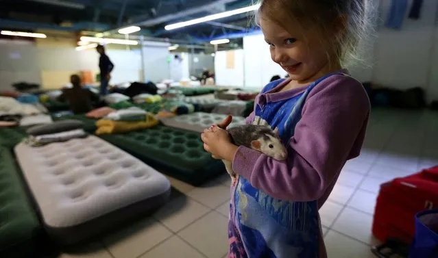 Olivia, 2, holds her rat Maja after arriving together with her relatives from Kyiv, at a temporary accommodation for people fleeing the Russian invasion of Ukraine, in Rzeszow, Poland, March 12, 2022. (Photo by Fabrizio Bensch/Reuters)