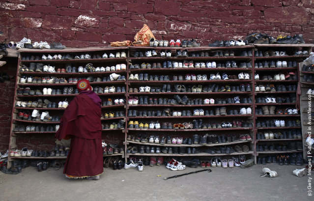 A nun puts her shoes on a shelf before she enters a Buddhist hall at the Serthar Wuming Buddhist Study Institute