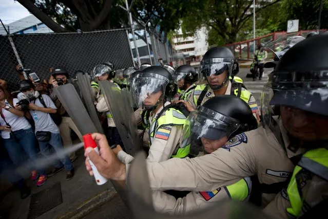 A Bolivarian National Police officer aims pepper spray at opposition leader Henrique Capriles during a protest in Caracas, Venezuela, Tuesday, June 7, 2016. Capriles was repulsed by police who threw tear gas when opposition leader and hundreds of demonstrators were trying to enter the main Caracas Highway to march towards the headquarters of the National Electoral Council or CNE to demand the government allow it to pursue a recall referendum against President Nicolas Maduro. (Photo by Fernando Llano/AP Photo)