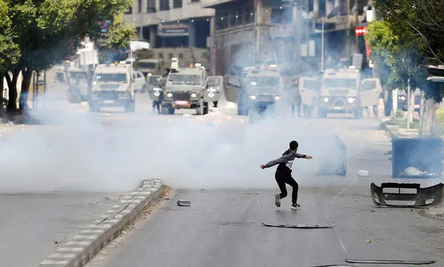 Palestinians throw stones at Israeli troops during clashes in the West Bank city of Nablus, 13 April 2022. According to Palestinian medical sources, 35-year-old Mohamed Assaf was killed during clashes with Israeli forces raiding in Nablus city earlier in the day. (Photo by Alaa Badarneh/EPA/EFE)