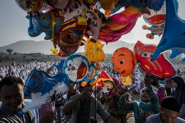 Indonesian Muslims buy balloons as attend Eid Al-Fitr prayer on “sea of sands” at Parangkusumo beach on June 25, 2017 in Yogyakarta, Indonesia. Eid Al-Fitr marks the end of Ramadan, during which Muslims in countries around the world spend time with family, offer gifts and often give to charity. (Photo by Ulet Ifansasti/Getty Images)