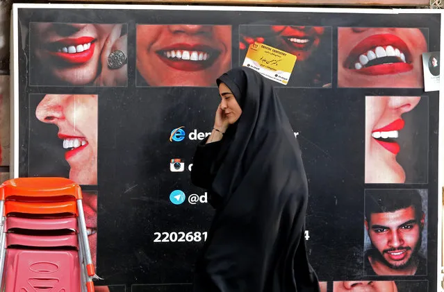 An Iranian woman walks past a bilboard as she talks on the phone in the capital Tehran, on November 27, 2019. Iran's supreme leader Ayatollah Ali Khamenei praised the country's people for foiling a “very dangerous” plot after violence erupted during protests this month against a fuel price hike by as much as 200 percent, as protesters attacked police stations, torched petrol pumps and looted shops, before being quashed within a few days. (Photo by Atta Kenare/AFP Photo)